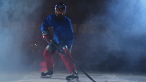 Man-hockey-player-with-a-puck-on-the-ice-arena-shows-dribbling-moving-directly-to-the-camera-and-looking-straight-into-the-camera